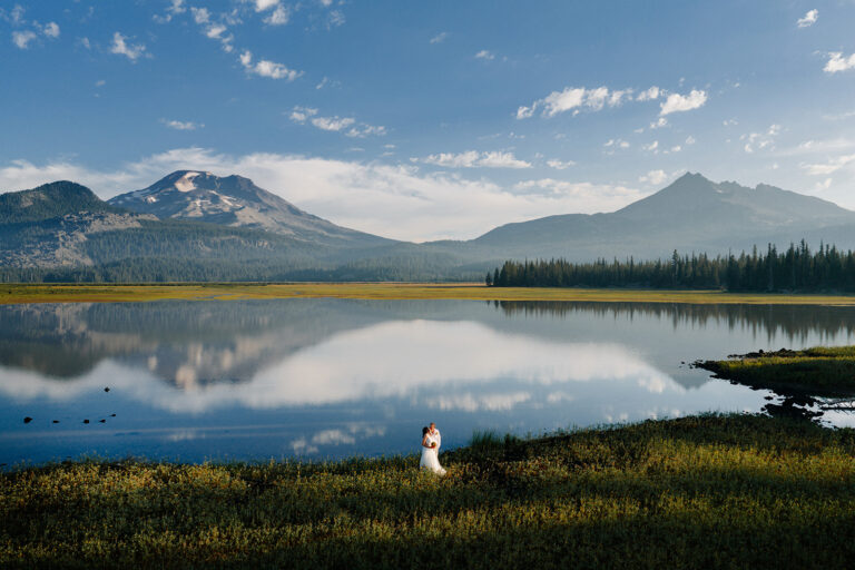 Couple beside Sparks Lake with mountains reflected in the water at sunrise